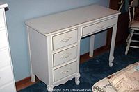 Front view of white wooden desk showing three stacked drawers on left and wide drawer on right, curved legs, and scalloped top edge.