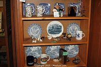 Shelf display with assorted coffee mugs, candle holders, animal figurines, Ridgeway Ironstone and Willow plates, and a decorative glass item.