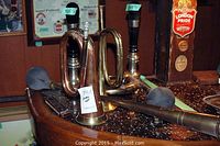 Two vintage brass and copper air horns displayed on a bar surface showing their full structure and rubber bulbs.