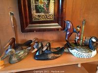 Shelf with five carved wood decoys, carved dolphin, man figurine, and coaster set