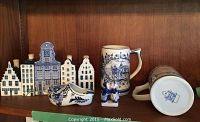 Full set including 5 ceramic buildings, 2 mugs, shoe, and kissing figure displayed on wood shelf.