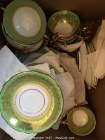 Contents of cardboard box showing stacks of plates and cups wrapped in tissue.