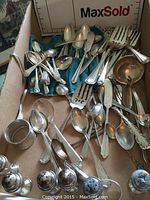 Box of assorted sterling silver spoons, forks, ladles, pie server, napkin ring, and shakers on teal cloth