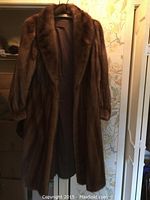 Front view of full-length brown mink fur coat on hanger