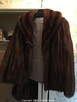 Full view of the mid-length brown fur coat showing the texture and length of the fur.