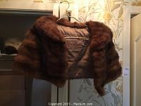 Brown fur shawl hanging on a hanger, showing overall shape and texture.