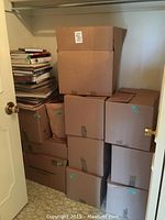 Stack of ten sealed and labeled cardboard boxes in a closet