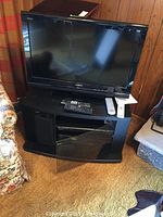 Full setup showing TV on cabinet with DVD/VHS decks and remotes