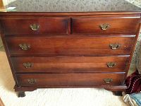 Front view showing mahogany finish dresser with four drawers and brass handles, visible scratches on surface.