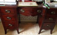Full front view of mahogany desk showing two pedestal supports and center scalloped apron