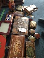 Overview of lot showing various decorative boxes, including lacquered box with musical instruments, set of Matryoshka dolls and multiple inlay wood boxes.