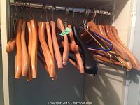 Wooden clothes hangers on a metal rod, some with belt/tie carry bars.