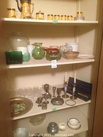 Full view of three shelves showing Carlton Ware tea set on top, vases and planters middle, crystal glasses and metalware below