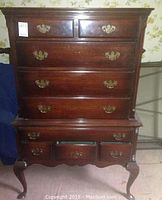 Front view of two-section mahogany finish highboy dresser, all drawers closed