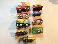 Top down view of nine toy vehicles on light surface showing Tonka and Tootsie Buddy L brands, includes dump truck, cement mixer, fire truck and small cars.
