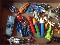 Box with assorted action figures, PEZ dispensers, and two toy cars without feet