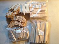 Photo of various Thomas wooden train tracks including straight and curved pieces, some loose and some packaged.