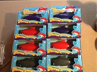 Eight battery operated swimming squirting dolphins in original packaging, arranged in two columns and four rows, showing a mix of red, black, and dark blue dolphins