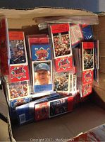Photo showing a box filled with multiple unopened packs and loose Talking Baseball Cards from the Topps Baseball Talk series featuring baseball player images and logos.