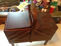 Closed view of the dark brown wooden vintage sewing chest showing its hinged compartments and handle