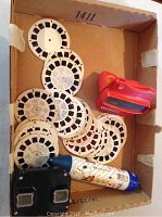 Box containing multiple vintage View-Master reels and three distinct View-Master viewers.