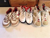 Three pairs of Nike and Jordan sneakers on a white surface in front of a wooden cabinet