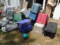 Image of assorted plastic storage tubs and lids outdoors on grass, various colors and sizes visible with a ball in front.