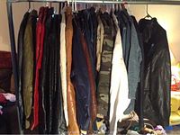 Jackets and coats hanging on a rack showing variety of leather coats in black, brown, red, and tan.