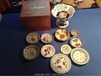 Photo showing set of large vintage candy dish and various vintage decorative plates arranged on a blue surface with JAY & SONS box