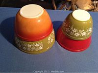 Four vintage Pyrex nesting mixing bowls upside down showing colored outer bases and floral patterns.