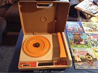 Photo showing vintage Fisher Price record player opened with orange turntable and lever.