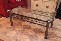 Glass and metal rectangular coffee table with rounded metal legs and diamond-shaped metal accent on side supports.