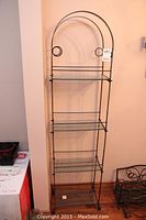 Full view of the metal 4-shelf display rack showing the arched top and wire shelves.