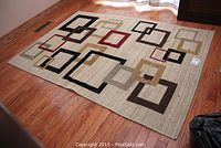 Full angled view of the rectangular rug on hardwood floor showing its multicolor square pattern and size.