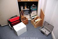 Wide shot of collection including cash drawer, file holders, and calculator inside shelving unit with papers and folders