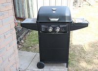 Front view of the Tera Gear propane BBQ grill showing two control knobs, side shelves, and wheels at the bottom.