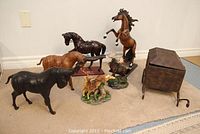Group photo of animal figurines including horses, bulls, a moose, a deer, and a covered metal storage box.