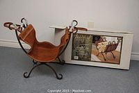 Front angle of new wrought iron log holder with leather sling and original box in background.