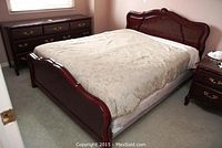 Photo showing full bed with wooden headboard, footboard, and mattress in bedroom setting.