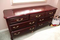 Full front view of the wood dresser showing seven drawers with brass handles.