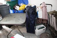 Photo showing square garden table, tent bag, plastic bins, and some bags.