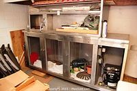 Full view of stainless steel commercial beer cooler base with under-door storage and exposed refrigeration compressor.