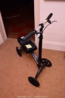 Full view of black In Motion mobility scooter with seat and handlebar, three wheels visible.