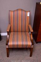 Front view of the armchair showing striped fabric seat, back and wooden armrests and legs