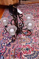 Full view of 5-arm light fixture laid on carpet, showing metal frame and frosted glass bulbs.