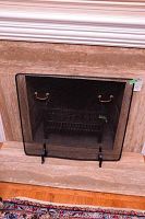 Glass fireplace screen placed in front of a fireplace opening used to prevent sparks and debris from entering the room.