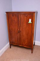 Front view of closed armoire showing wood grain, panel doors and hardware