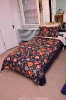 Single bed arranged and made up with floral duvet and pillow covers in bedroom with radiator and window