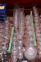 Various clear glass drinking glasses arranged in rows on a surface