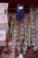 Overview of assorted glassware on table including boxed Claudia Bohemian Crystal sherry glasses and unpackaged stemware arranged in rows.
